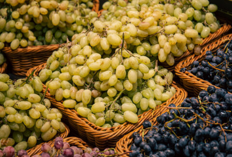 Baskets with different types of grapes on a supermarket showcase.