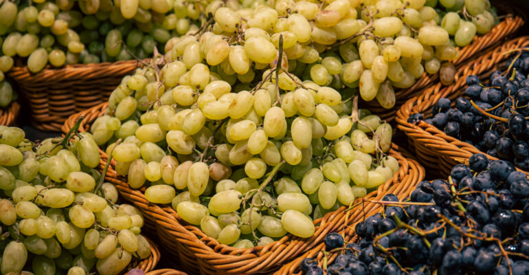Baskets with different types of grapes on a supermarket showcase.